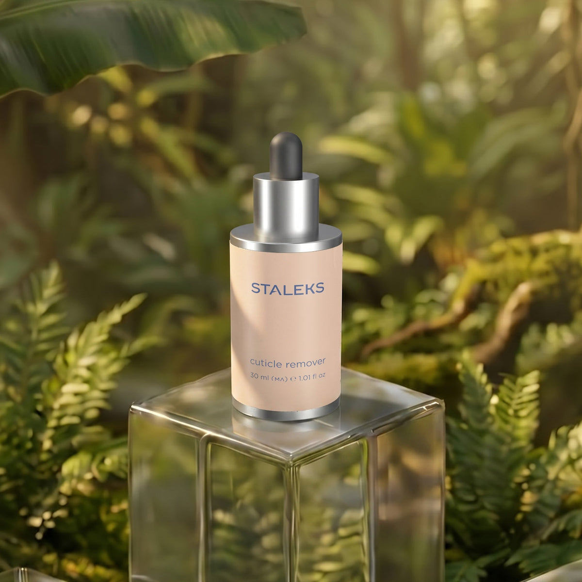 STALEKS Cuticle Remover 30 ml kynsinauhojen pehmentämiseen. Pipettipullo lasisella korokkeella vihreiden kasvien ympäröimänä.